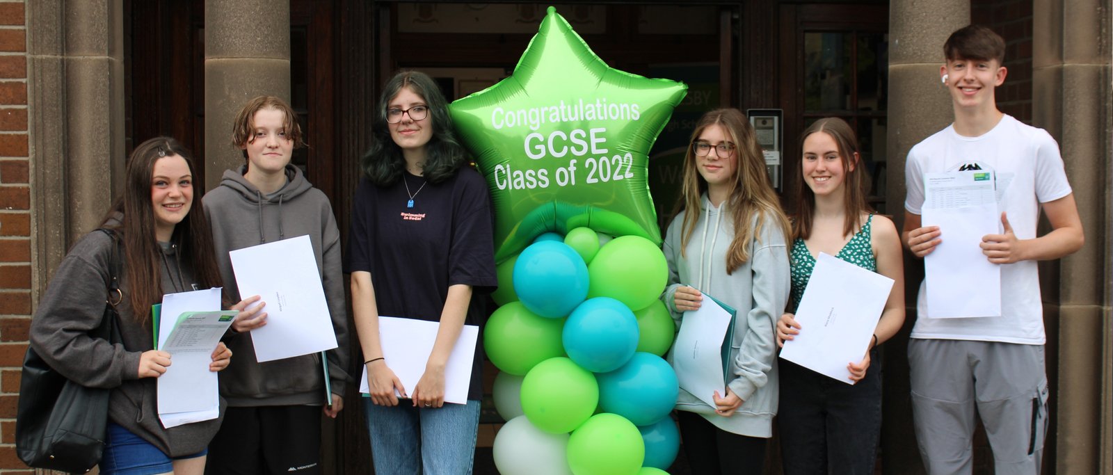 GCSE students outside school receiving their results.